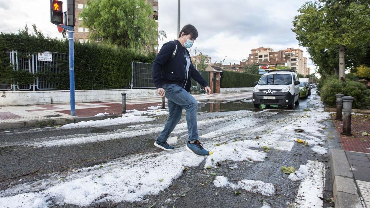 Un joven trata de cruzar una calle con precaución sobre el hielo que dejó la tormenta.  | RAFA ARJONES