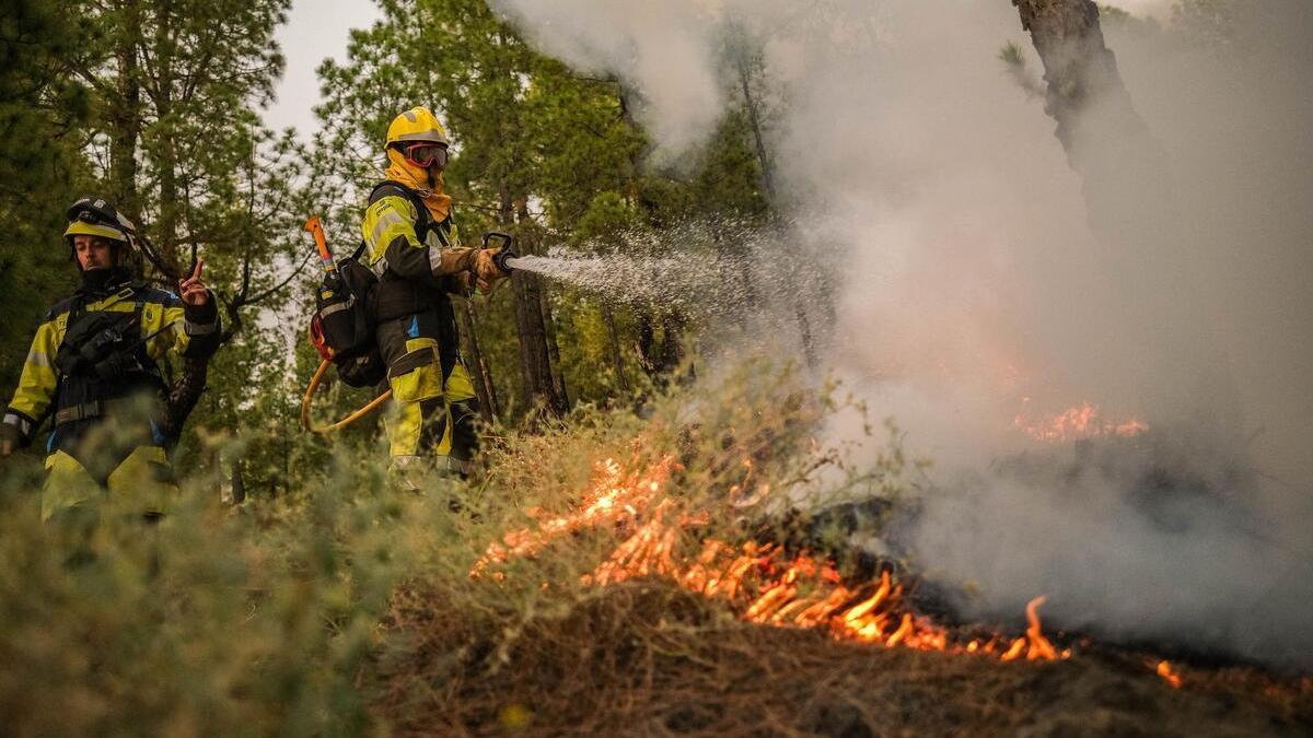 Los bomberos extinguen el fuego durante el incendio de La Palma