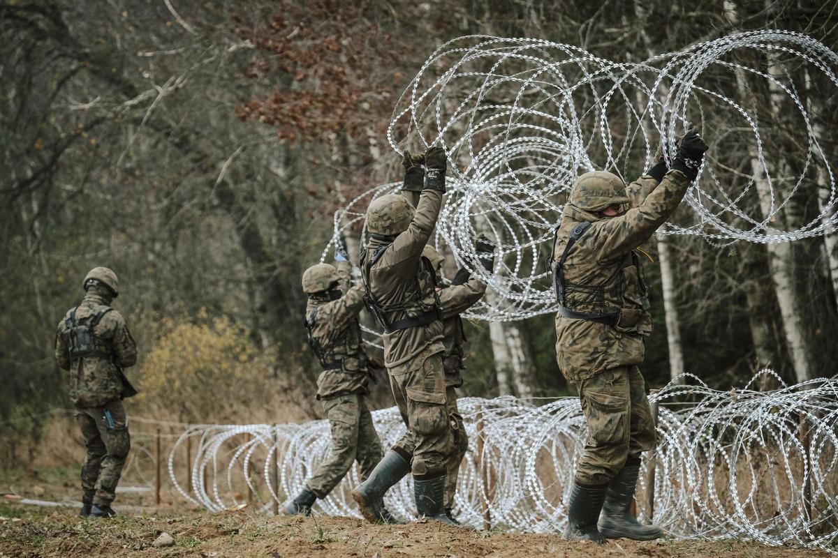 Soldados del ejército polaco arreglan bobinas de alambre de púas en una valla a lo largo de la frontera polaca, con el enclave ruso de Kaliningrado, cerca de Zerdziny, Polonia