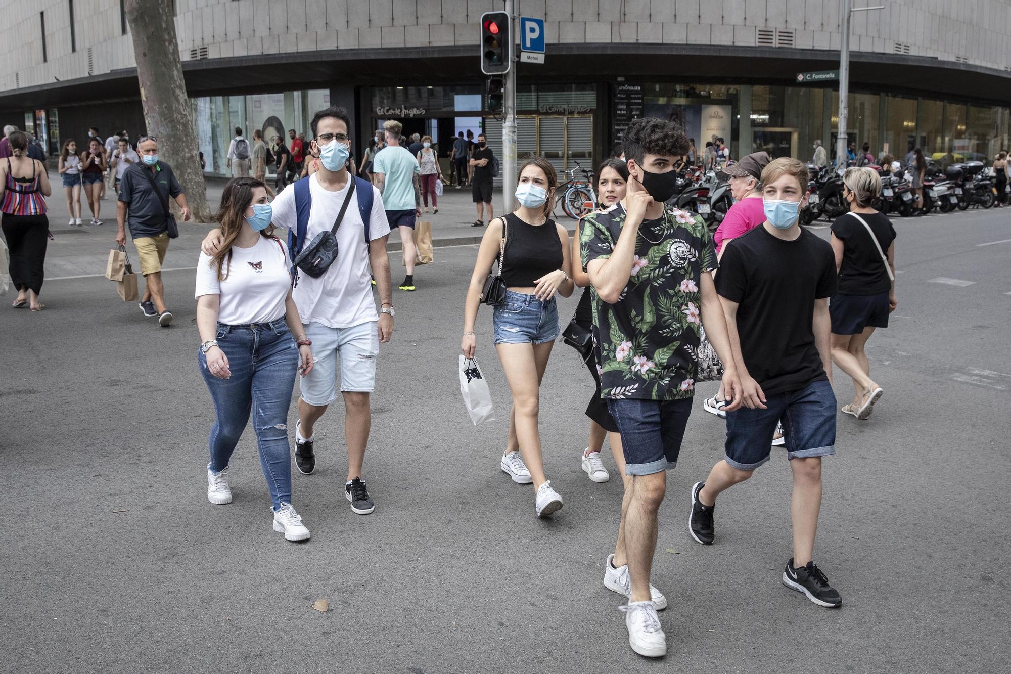 Jóvenes paseando con mascarilla puesta en Barcelona.