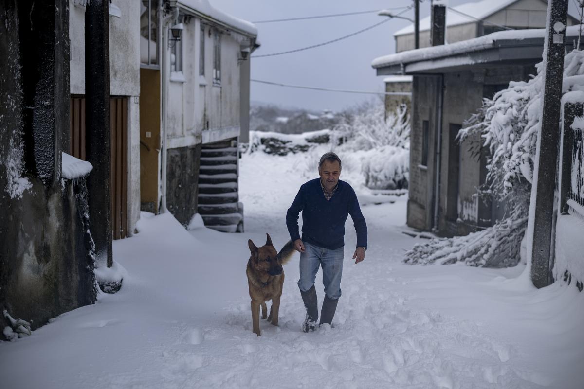 SAN XOÁN DE RÍO (OURENSE), 18/01/2023.- Un hombre camina junto a su perro sobre un camino nevado en una aldea de San Xoán de Río (Ourense), este miércoles. Un total de 1.378 han sido los incidentes contabilizados en Galicia desde el día 16, inicio del temporal, hasta lo que va de la jornada de este miércoles, en todos los casos a causa de los efectos del viento, la nieve y la lluvia. EFE/ Brais Lorenzo