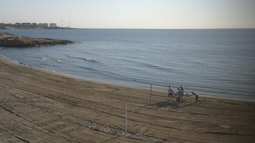 Los sanitarios retiran el cadáver de la orilla del mar.