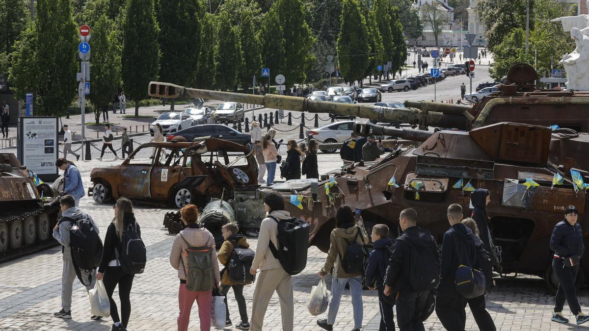 Varias personas caminan entre material militar ruso destruido y vehículos civiles ucranianos en Kiev.