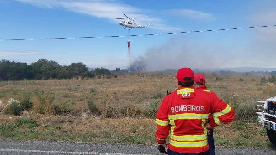 Los bomberos observan cómo un helicóptero echa agua al monte verinense. // FdV