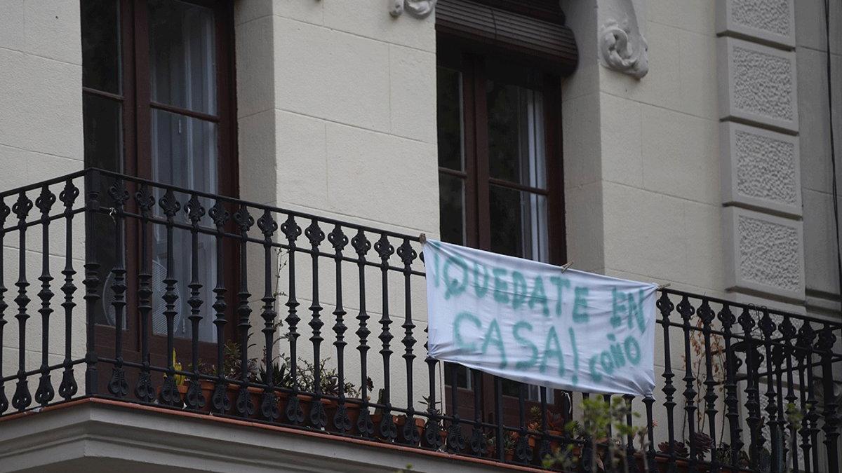 Cartel animando a cumplir el confinamiento en casa, en un balcón de Barcelona, el 22 de abril