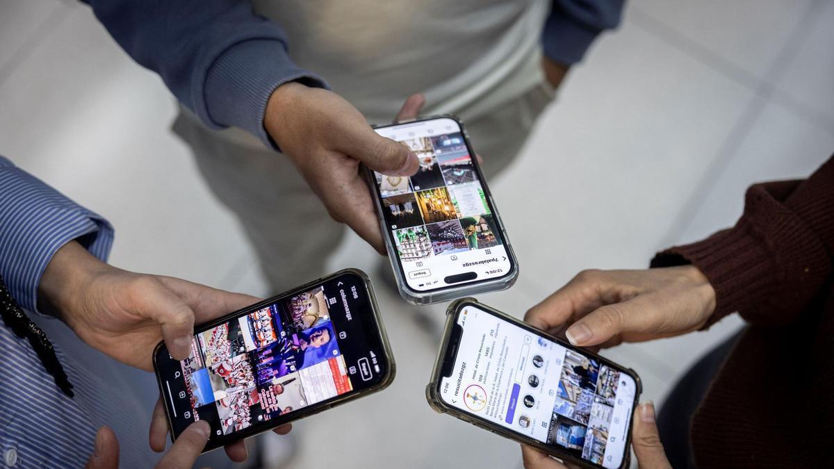 Tres personas miran sus redes sociales.