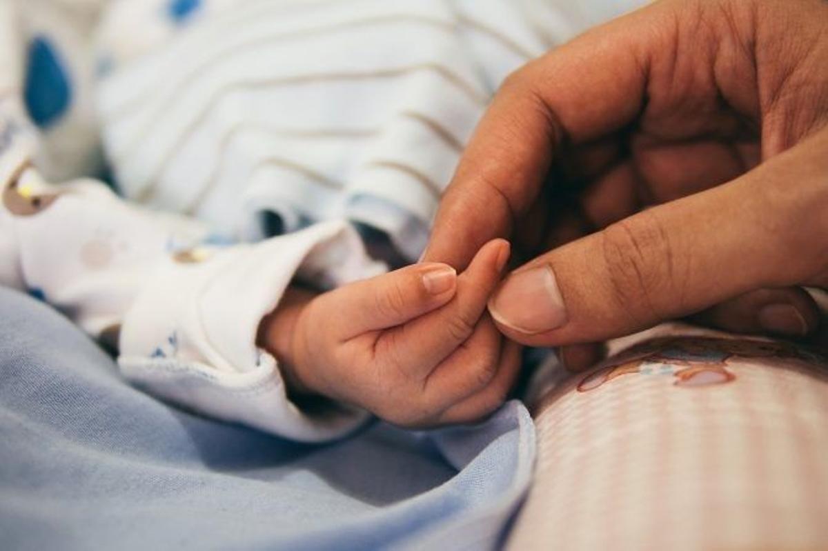 Una madre coge la mano de su hijo recién nacido.