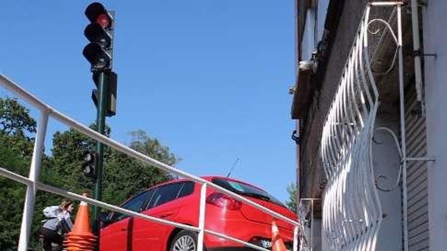 La parte trasera de uno de los vehículos (en la imagen) quedó suspendida frente a una vivienda tras salir despedido; el otro coche colisionó contra la verja del vial de servicio tras llevarse por delante una marquesina de bus y un contenedor. // Nick