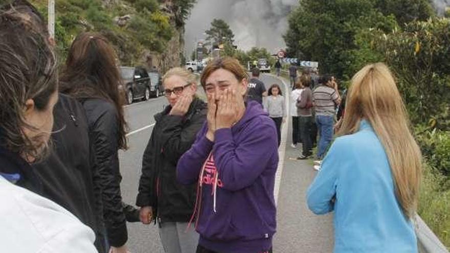 Mujeres llorando con el humo del incendio al fondo en 2016. // S.Á.