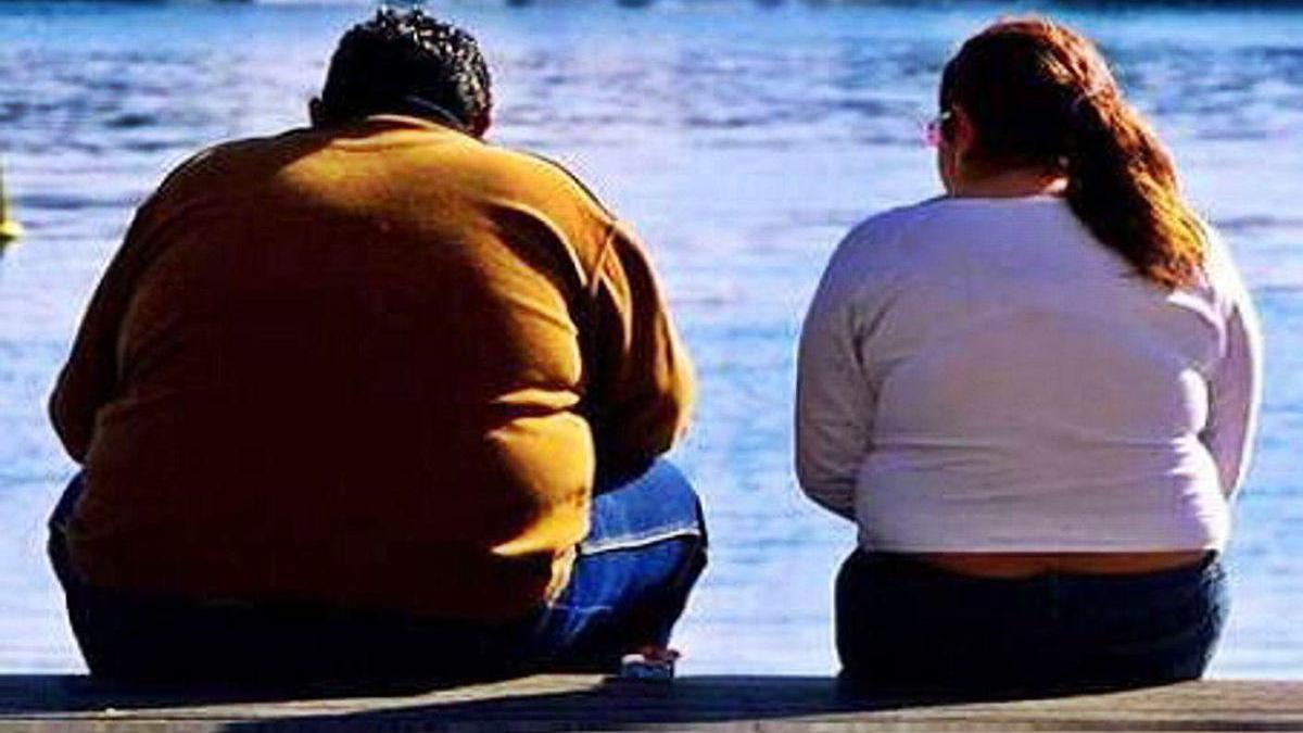 Dos personas con problemasa de peso, en un parque.