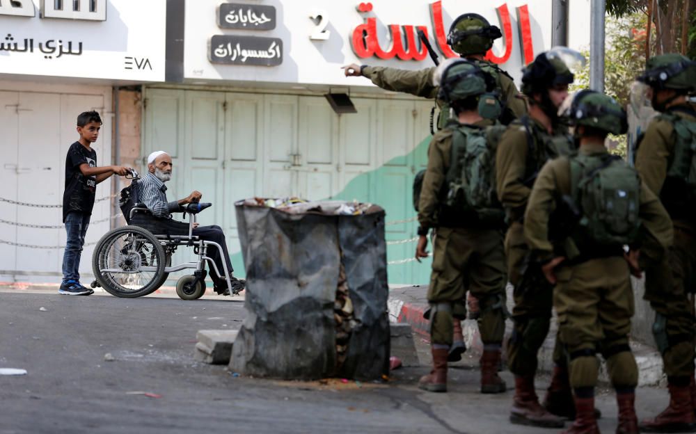 Un palestino en silla de ruedas es empujado durante los enfrentamientos entre los palestinos e israelíes en Hebrón.