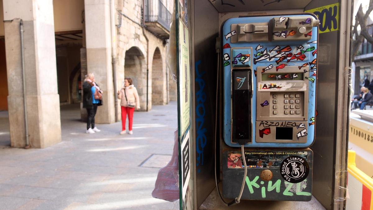 L'última cabina de telèfon que quedava a Girona, amb les voltes de la Rambla al fons