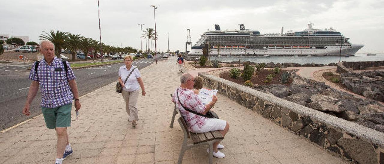 Unos turistas pasean por la avenida marítima con el buque crucero atracado en el muelle de Puerto del Rosario.