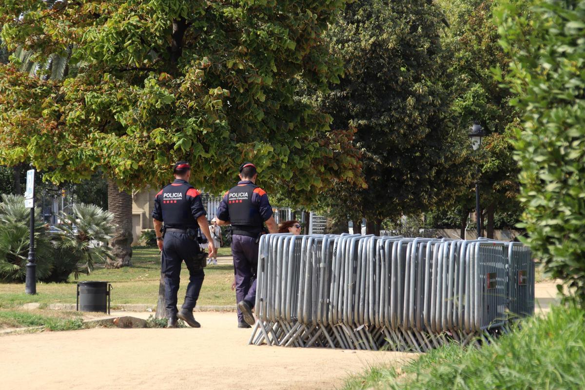 Dos agents dels Mossos caminen pel Parc de la Ciutadella i passen pel cantó de tanques metàl·liques.