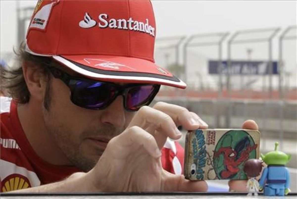 Fernando Alonso fa una foto amb el seu mòbil hores abans de començar el gran premi de Bahrain, en què el pilot asturià ha finalitzat en setena posició.