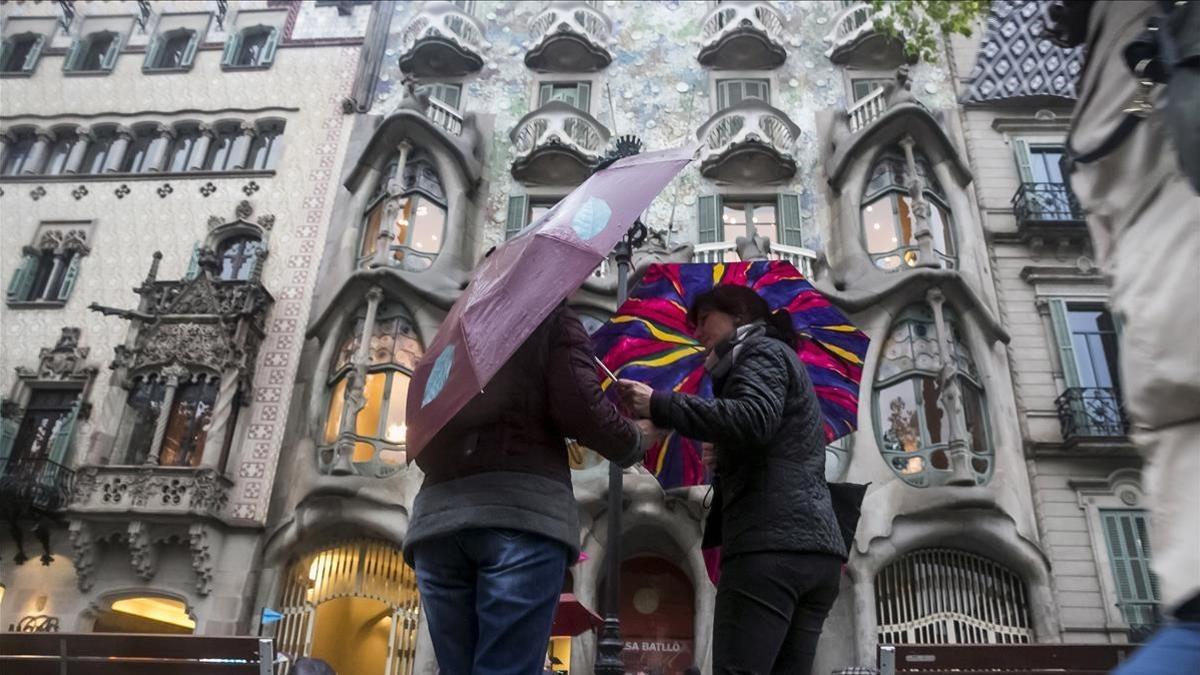 Dos chicas con paraguas frente a la Casa Batlló, en Barcelona.