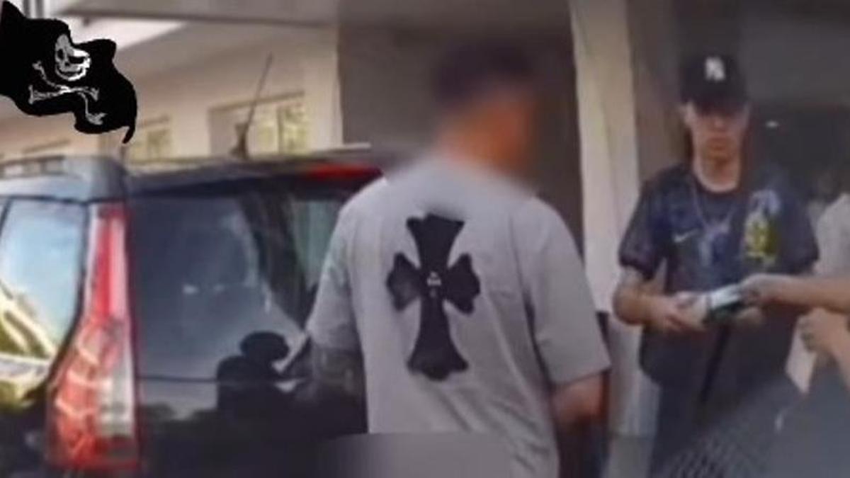 Momento en el que el cliente (hombre con gorra) paga los servicios al presunto taxista pirata (hombre con camiseta gris) en la puerta del hotel.