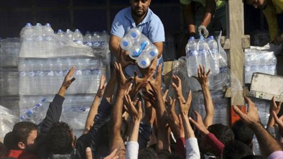 Los refugiados reciben agua en la frontera de Grecia y Macedonia.