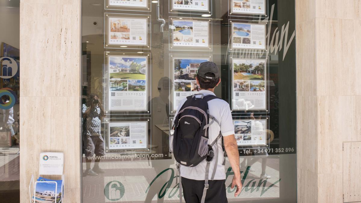 Un joven observa el escaparate de una inmobiliaria.