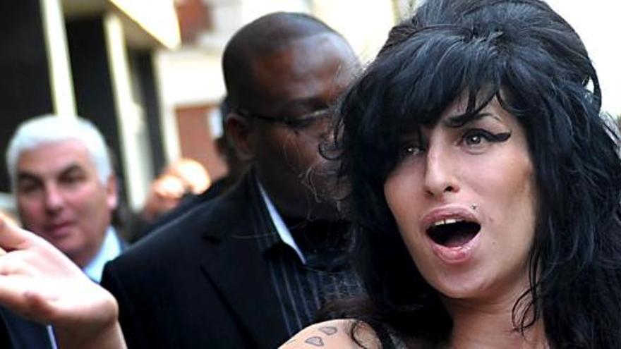 Amy Winehouse, con su padre detrás de ella.