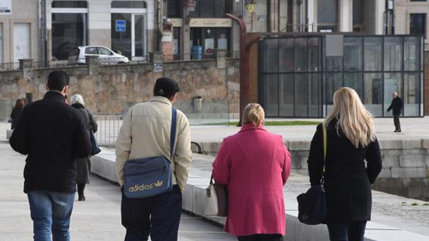 Varias personas pasean, abrigadas, por A Coruña.