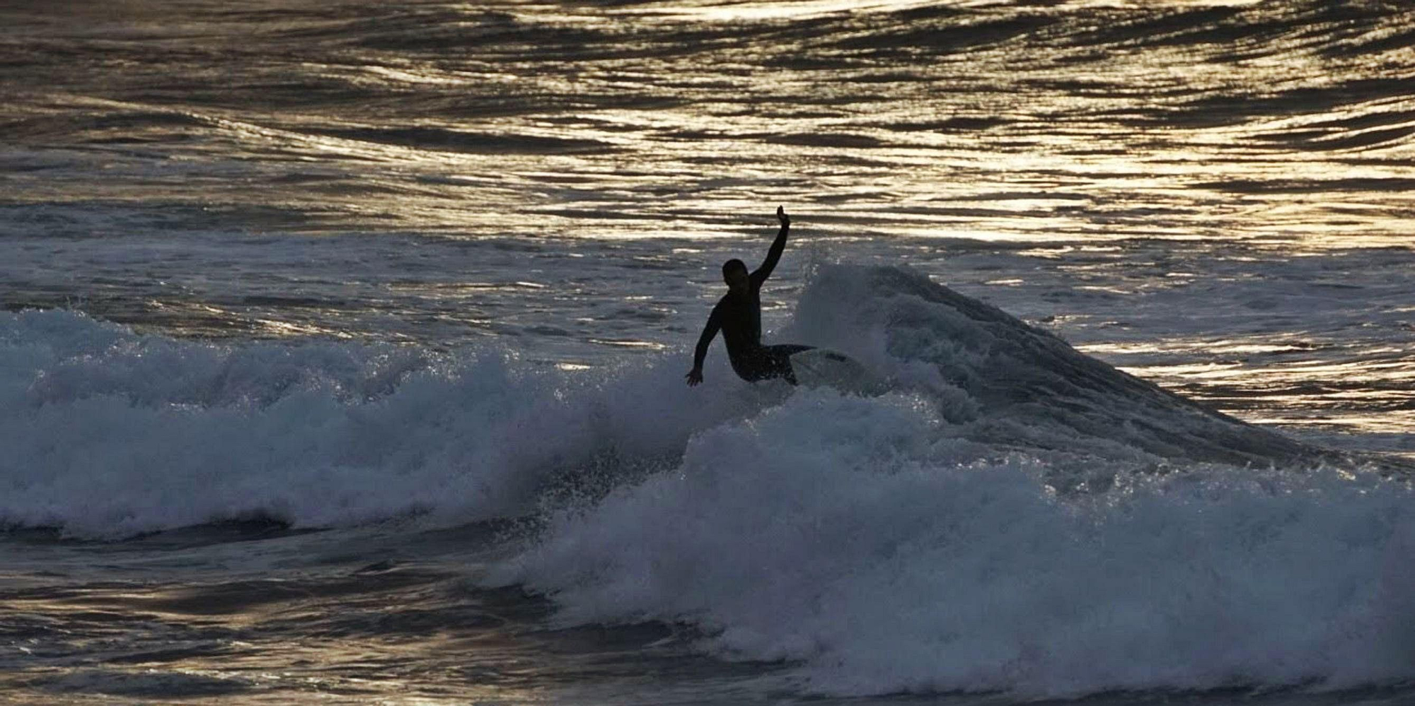 Un surfero disfturando de la ola de Vagabundos en el atardecer.