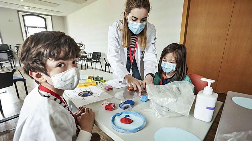 Carmen Huergo, del ISPA, ayuda a Manuel Pujante y a Sara Iglesias a hacer una célula con plastilina.