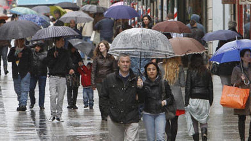 Personas paseando por el centro de Vigo en un día lluvioso.