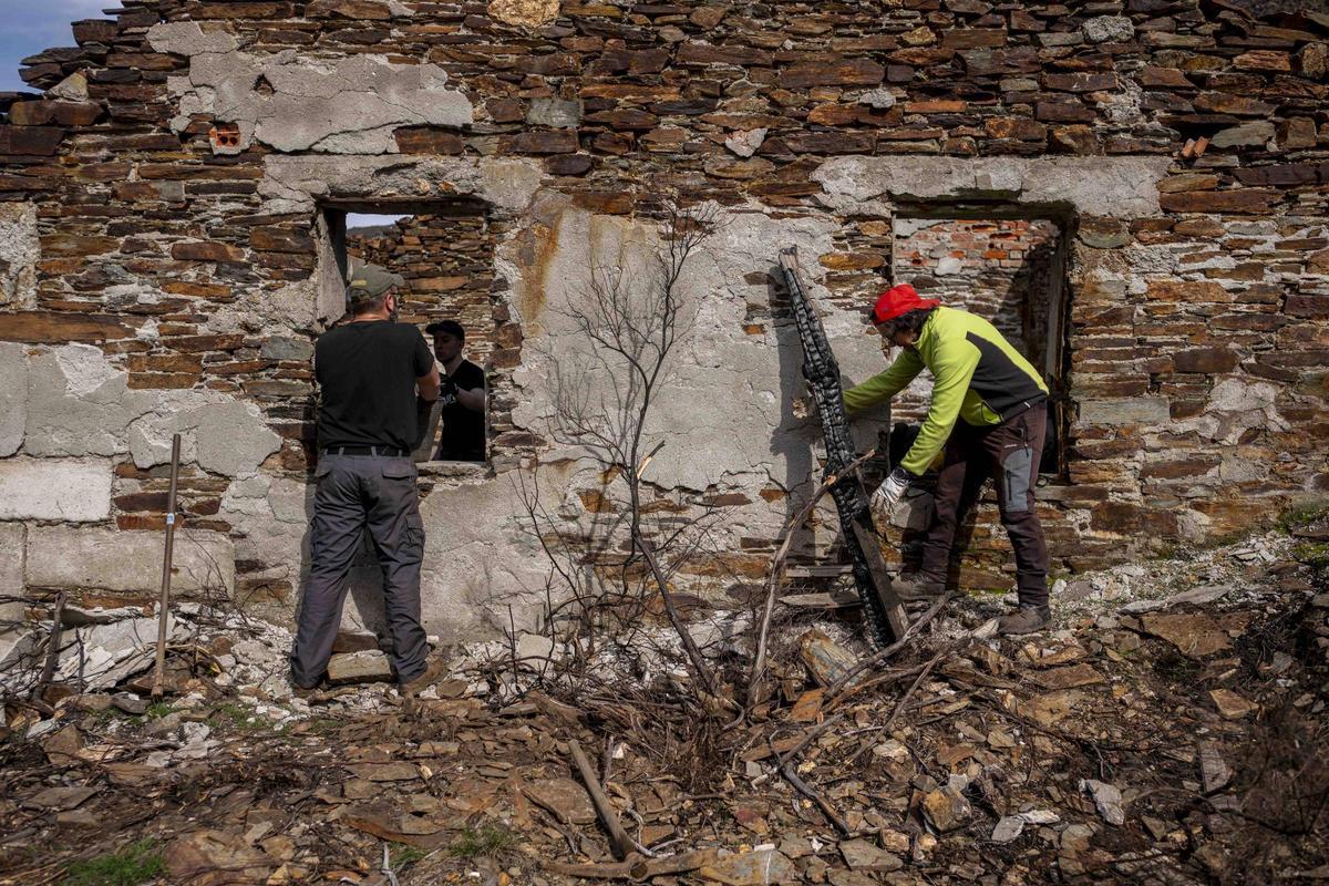 Un voluntario retira una viga quemada de una construcción de la antigua explotación minera.