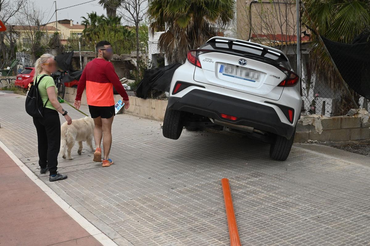 Dos personas miran el coche empotrado contra el muro.