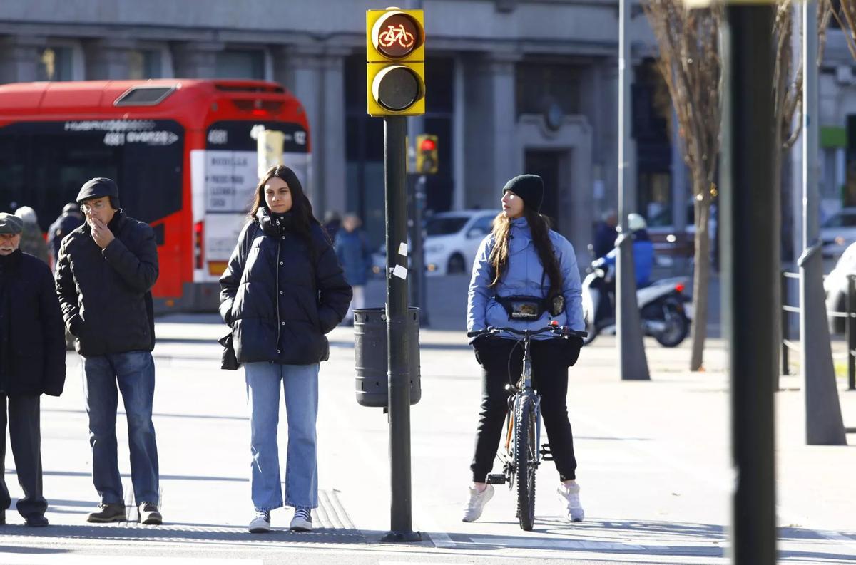 Peatones y una ciclista esperando para cruzar un paso de zebra