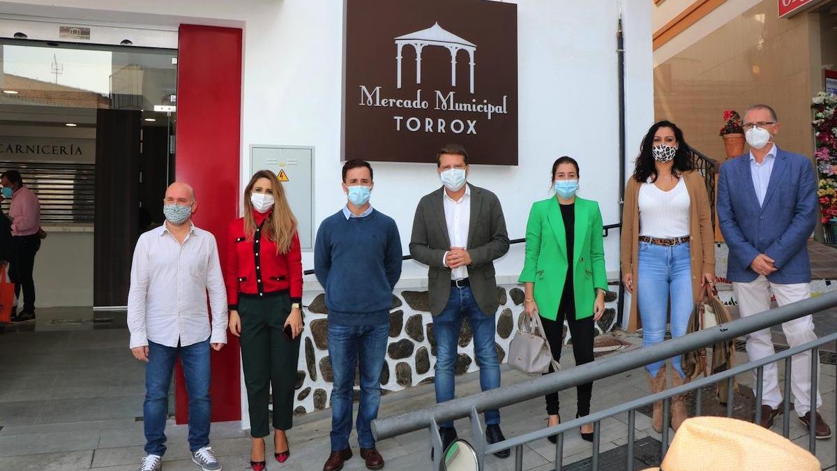 El alcalde, en el centro, y otros representantes municipales, frente a la puerta de entrada al mercado.