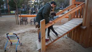 Un padre ayuda a su hija a acceder a un juego en los Jardines de la Industria de Barcelona.