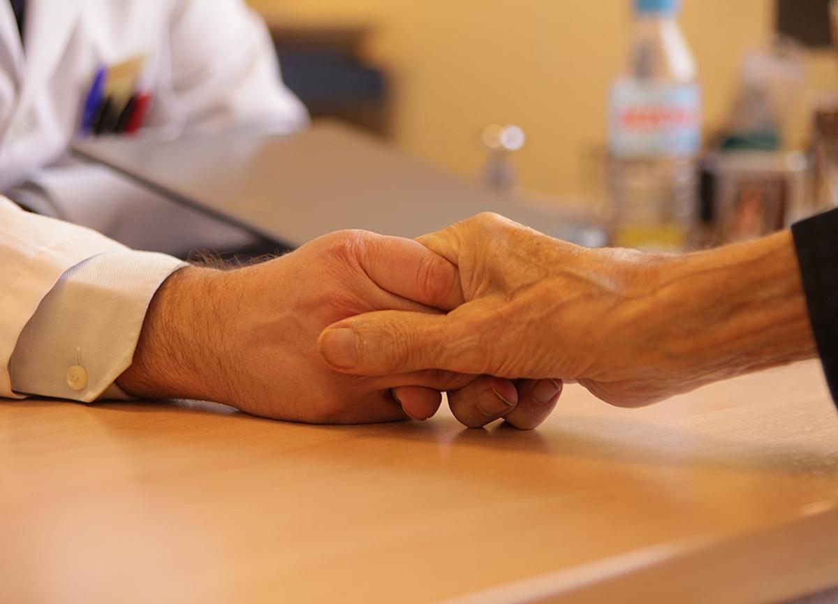 Un médico agarrando la mano de un paciente.