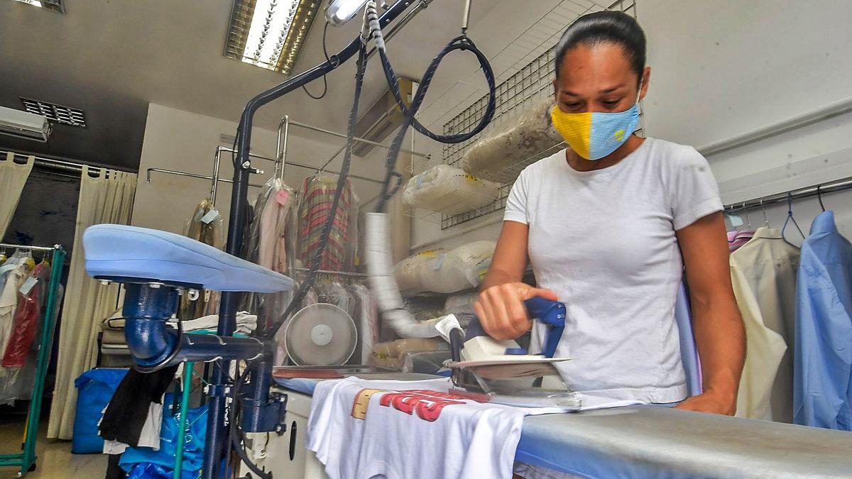 Una trabajadora de las tintorerías Brisamar plancha una camiseta . | | J.C.