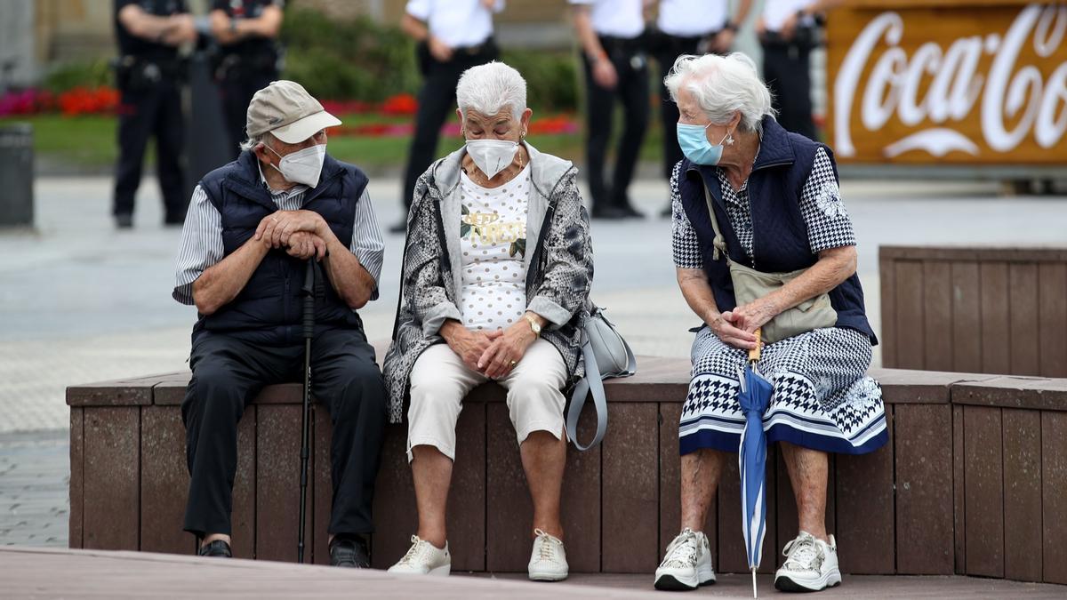 Unos ancianos conversan protegidos con mascarillas en San Sebastián