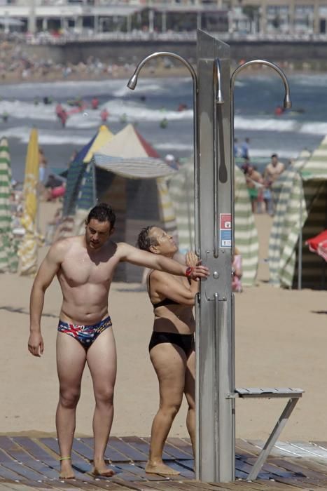 Gijoneses y visitantes se lanzan a la playa en una jornada calurosa.