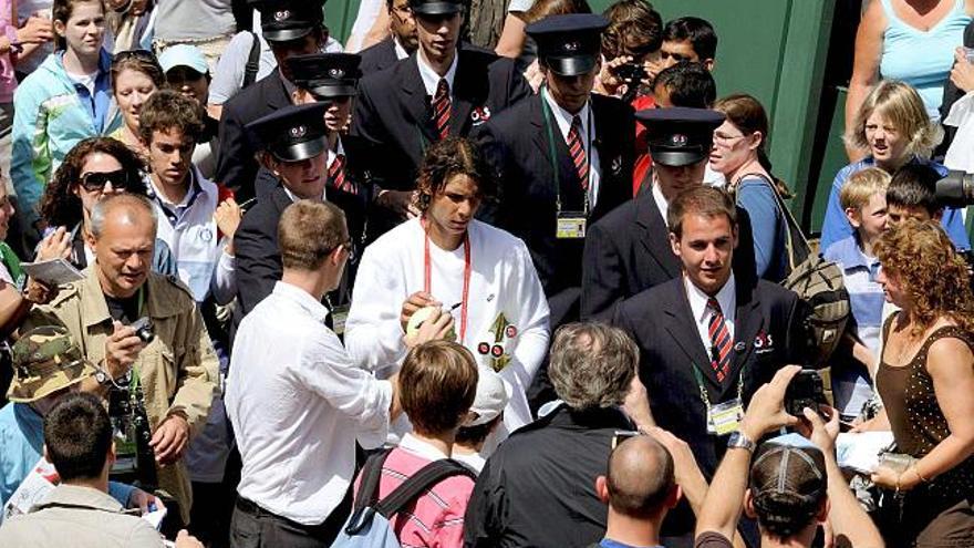 Nadal arrastra a las masas. Rafel Nadal -en la imagen rodeado de aficionados a la caza de un autógrafo del número 2 del mundo- toma ventaja de cara a la final de hoy con respecto a Roger Federer. Su entrenamiento, de casi una hora y media, en la pista 14 de las instalaciones de Wimbledon, fue seguido por multitud de aficionados que no dejaron de animar al campeón mallorquín. Su enorme carisma entre los jóvenes y no tan jóvenes quedó demostrado una vez más.