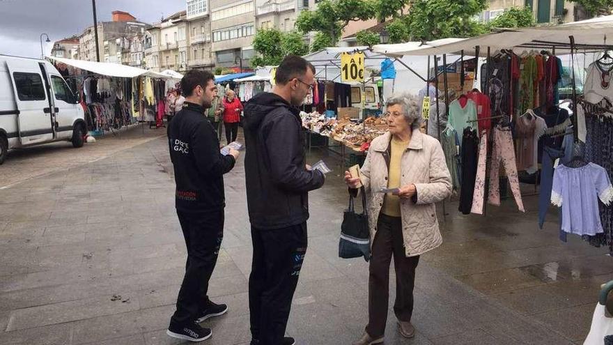 Rubén y Suso Soliño repartiendo folletos en el mercadillo. // G. Núñez