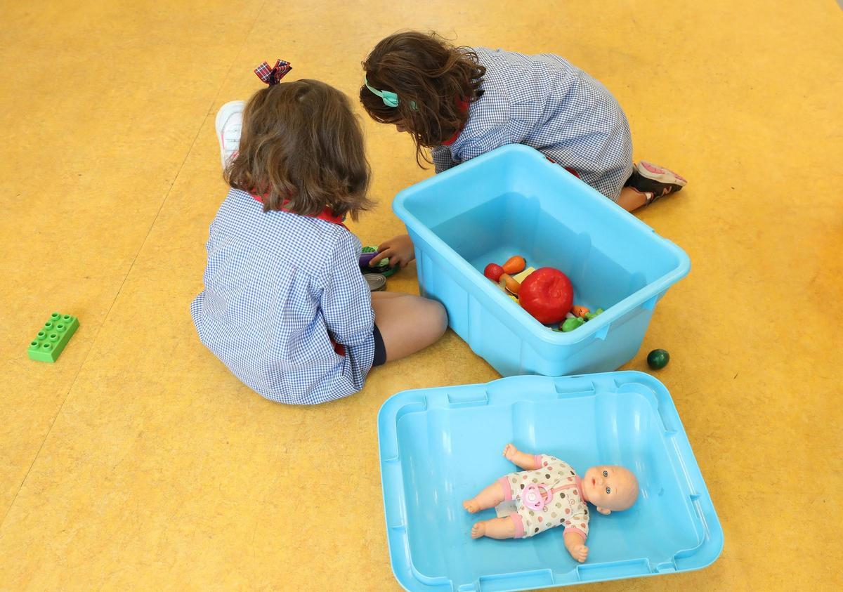 Dos niñas juegan en una escuela con muñecos
