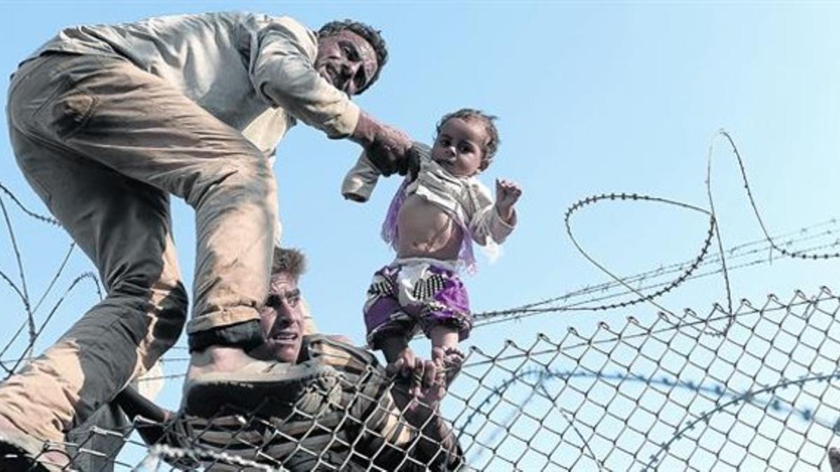 Refugiados sirios saltan una valla fronteriza en Akçakale, ayer.