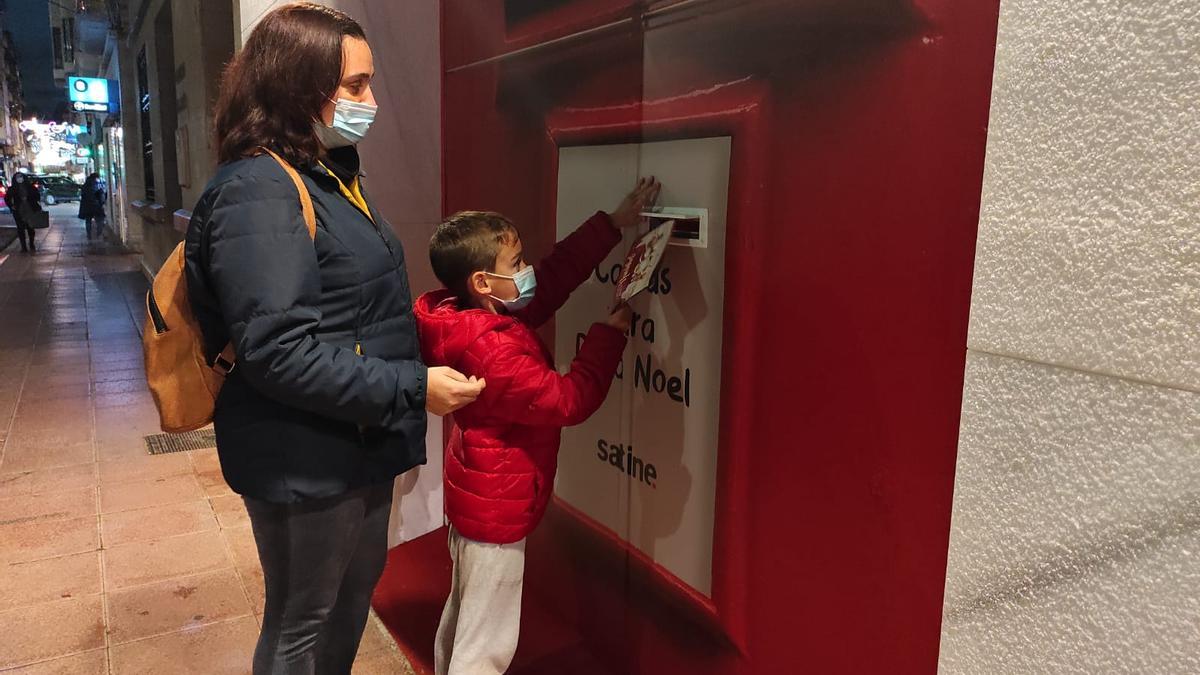 Un niño deposita su carta en el buzón que hay disponible en la Casa de Papá Noel que ha impulsado Satine.