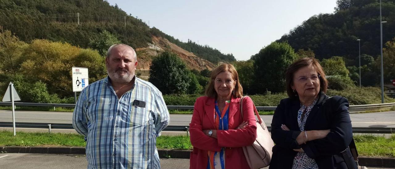 Por la izquierda, Fernando Álvarez, Maribel Rodríguez y María Victoria López, ayer, en Casazorrina, con las obras de la autovía Oviedo-La Espina al fondo. | S. Arias