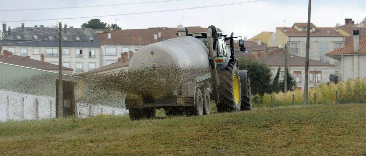 Un tractor con cuba esparciendo purín en una finca de Silleda.