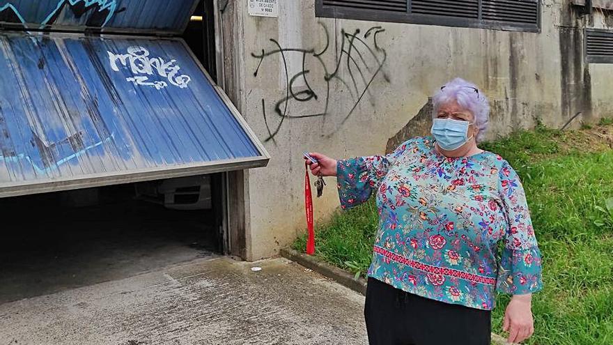 María Esther Vázquez muestra las pintadas en la entrada del garaje de uno de los bloques de AVN en La Corredoria. | F. V.