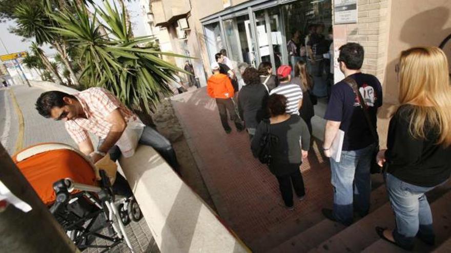 Varios ciudadanos esperan su turno en el exterior de una oficina del Inem en Alicante.