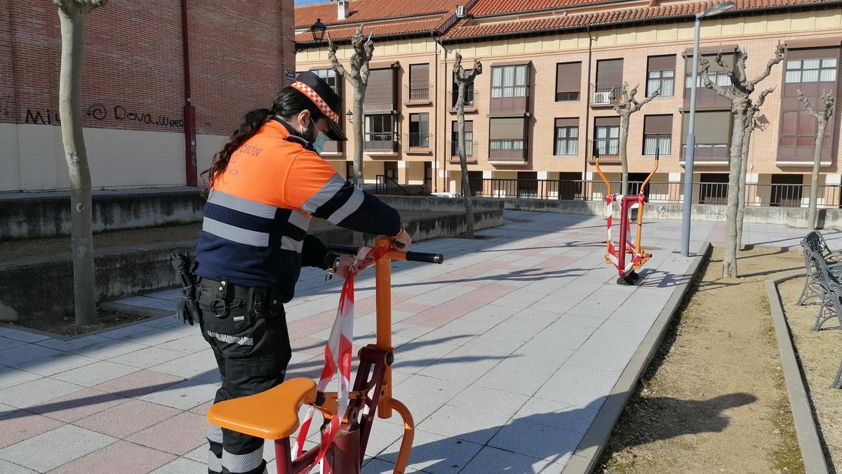 Un voluntario de Protección Civil retira el precinto de una zona biosaludable