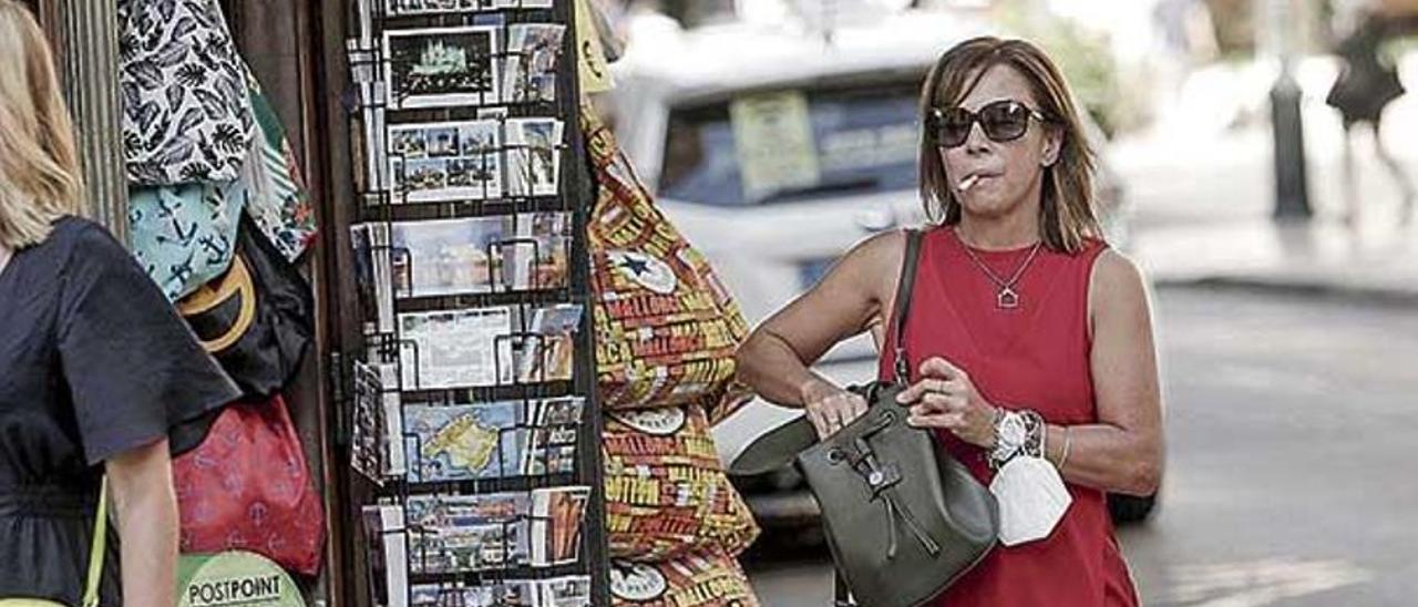 Una mujer sin mascarilla y fumando en la calle durante la prohibición.