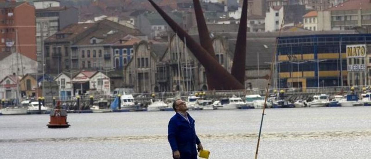 Un pescador de caña na marxe derecha de la ría, con &quot;Los Conos&quot; al fondu.