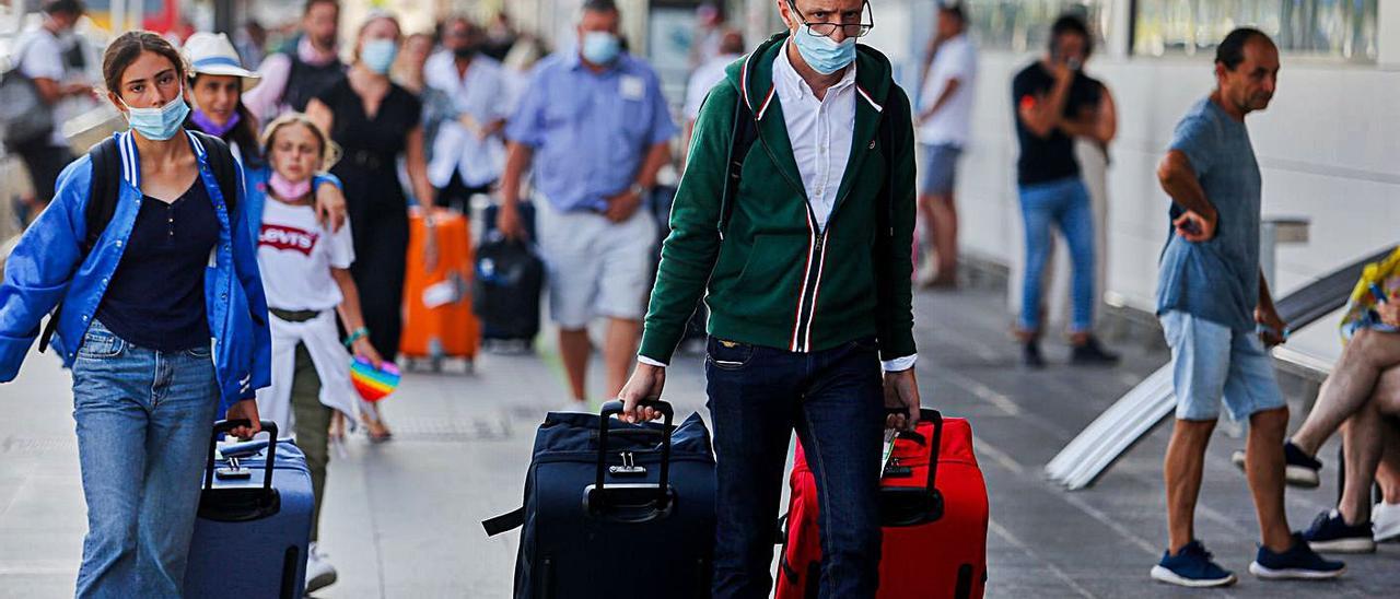 Un grupo de personas con sus maletas en el exterior del aeropuerto de Evissa. | TONI ESCOBAR